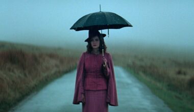 Sophie Rundle as Ada standing on the road and holding an umbrella in Peaky Blinders: The Immortal Man