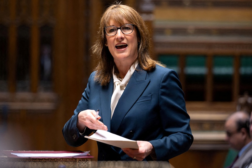 Rachel Reeves in a navy blue blazer and white top speaking while standing in the UK House of Commons chamber.