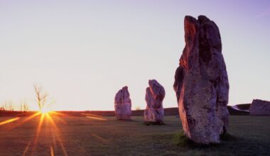 A series of stone pillars are seen in the setting sun overlooking a field