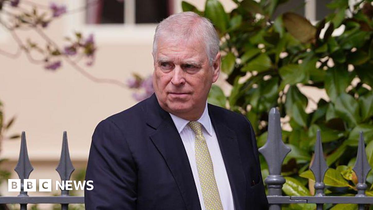 Andrew Mountbatten-Windsor wearing a dark-coloured suit with a white shirt and yellow tie