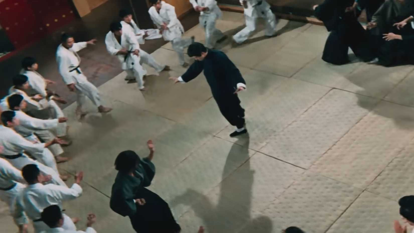 Bruce Lee surrounded by fighters in a dojo in Fist of Fury