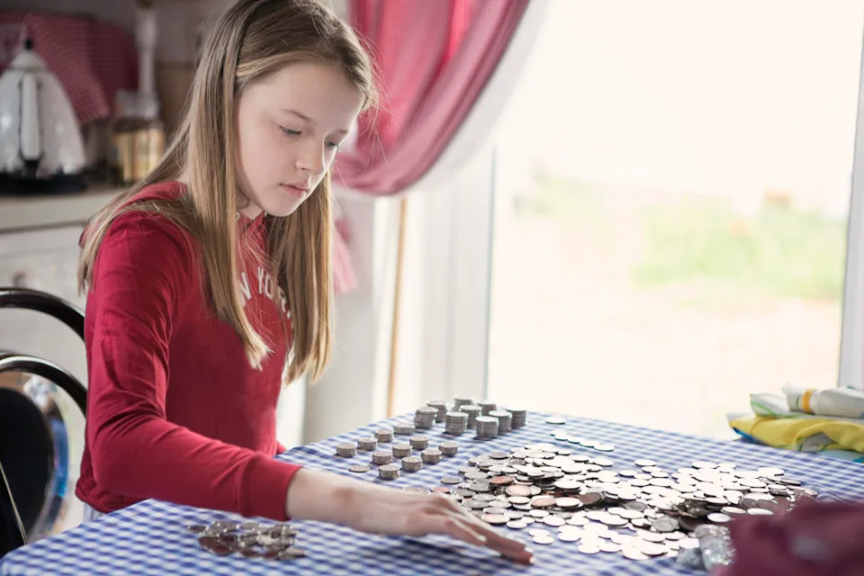 Girl counting pocket money coins on a table.