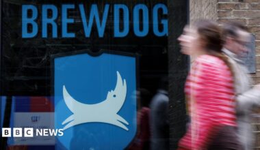 People walk past a closed-down BrewDog bar in central London. The window of the pub has the word Brewdog written in large blue letters above its logo, featuring a white dog on a blue background.