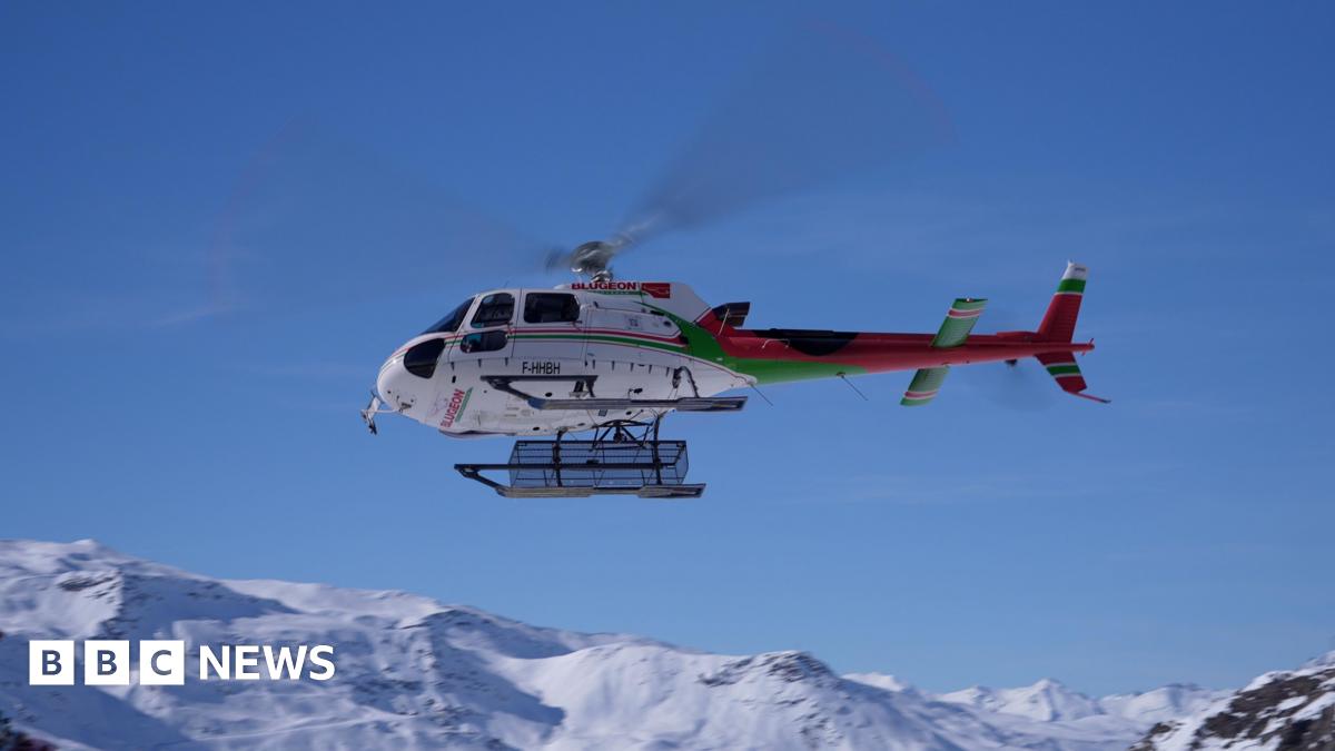 Stock image of a female climber wearing a backpack hanging onto a rock