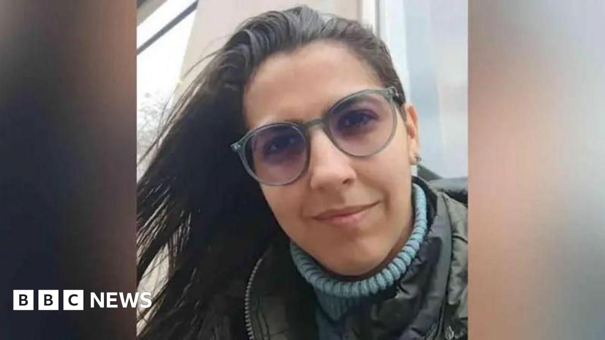 A picture shows the face of Barreto. She is wearing a blue turtleneck under a coat and glasses.