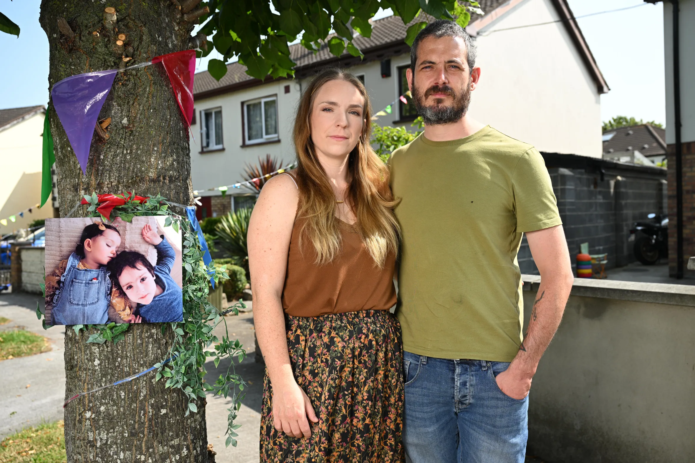 Gillian and Stephen Morrison stand next to a tree with a photo of their child, Harvey Morrison.