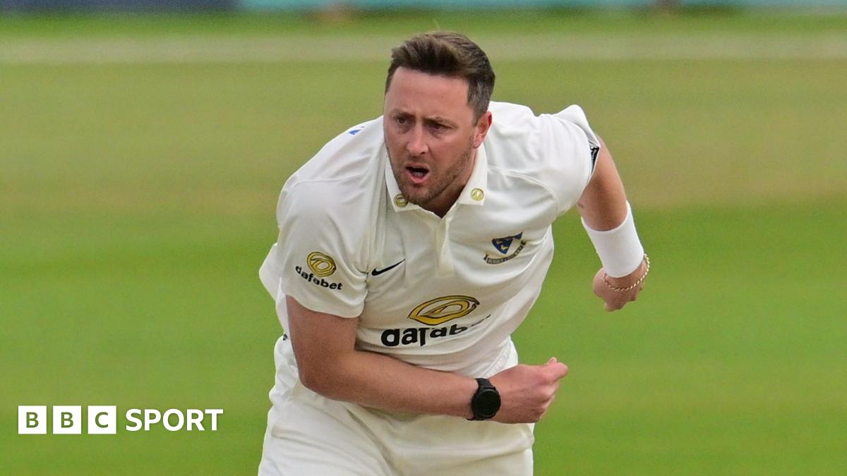 Ollie Robinson playing for Sussex and slightly hunched over with his right arm across his front and his left splayed to the back, having just completed a delivery.