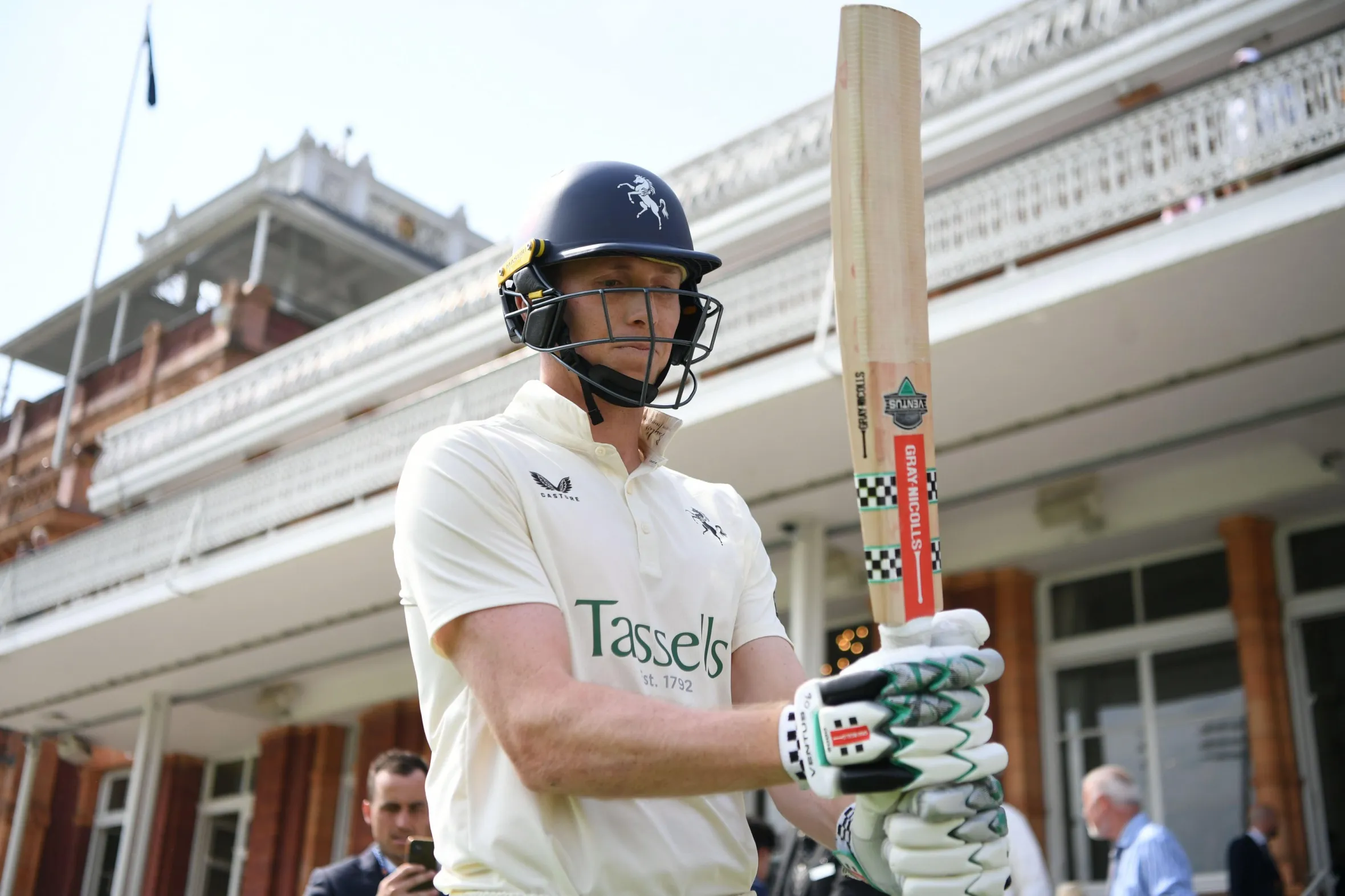 Zak Crawley in cricket gear, holding a bat at Lord's Cricket Ground.