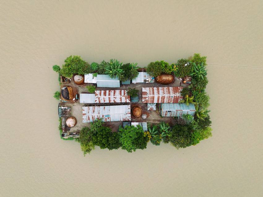 This isolated, island-like settlement features houses and livestock. The naturally elevated mound staands above the monsoon floodwaters