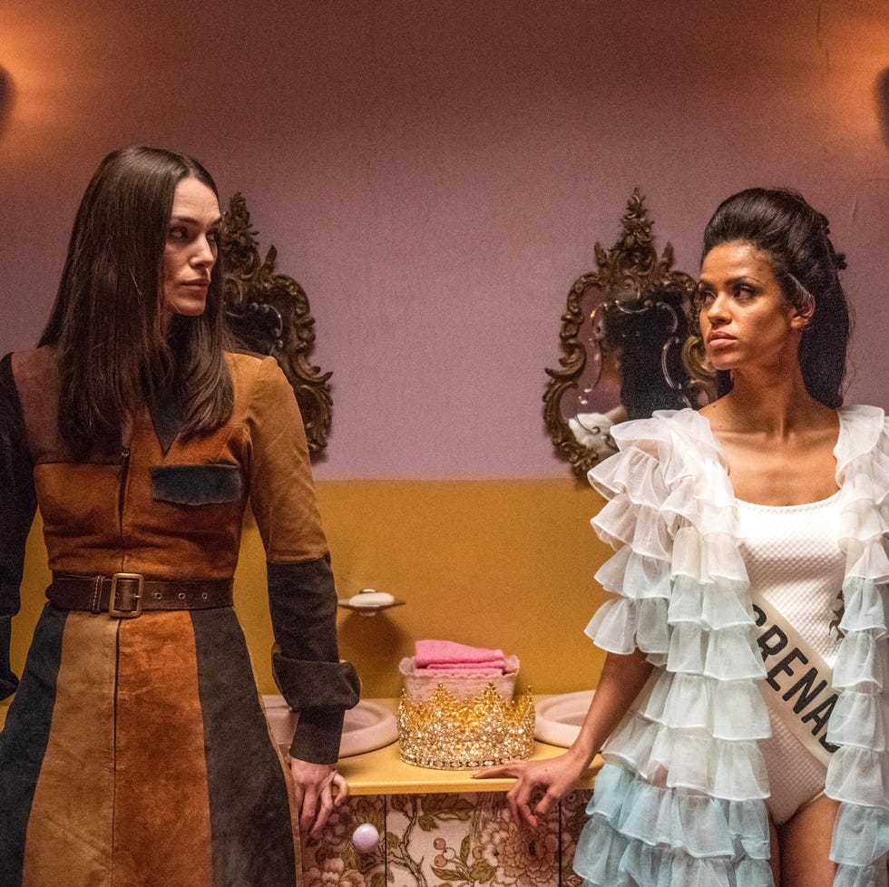 two individuals standing in a dressing room setting with a vintage aesthetic