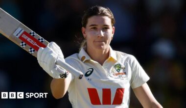 Australia batter Annabel Sutherland raises her bat to celebrate reaching a Test century against India