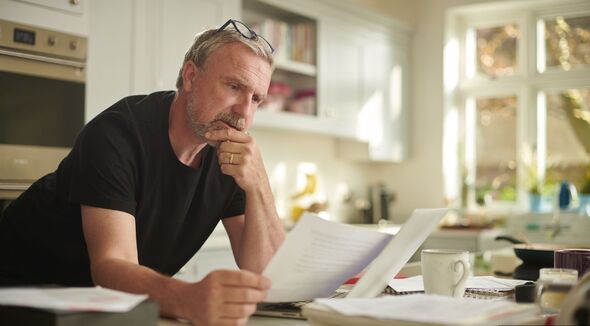 Man looks at paperwork at kitchen table