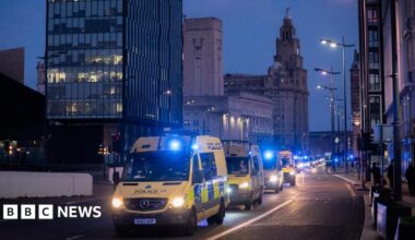 A convoy of yellow police vans in front of the Liver Building