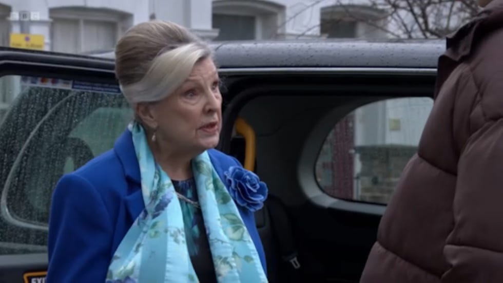 person in formal attire engaging with another individual near a vehicle