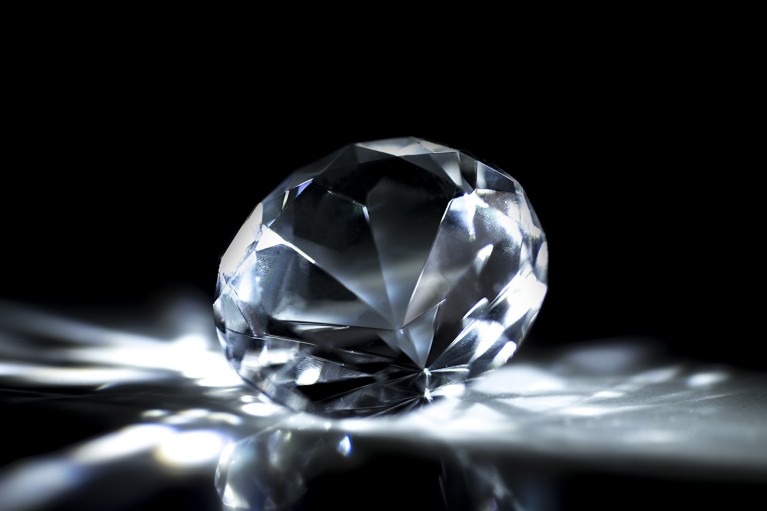 A single cut diamond stone with light reflecting around it on a black background.