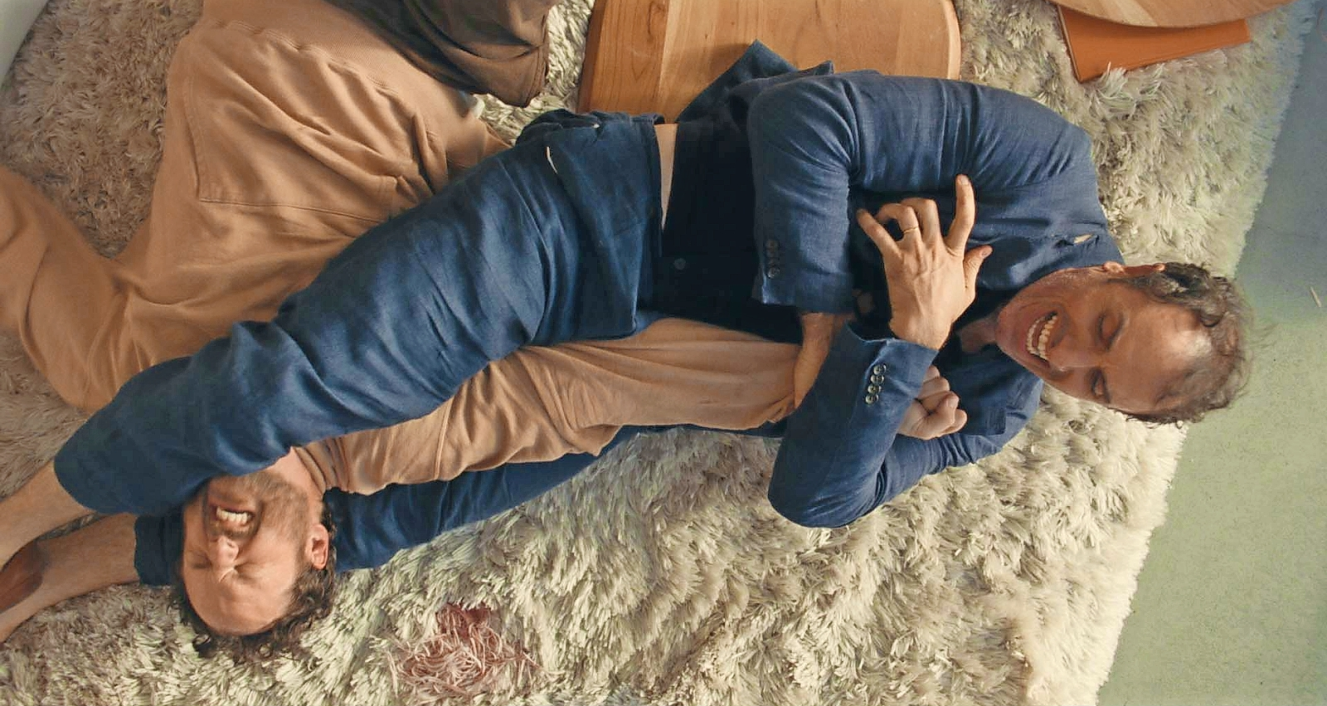 Kyle Marvin and Michael Angelo Covino wrestling on a shag rug.