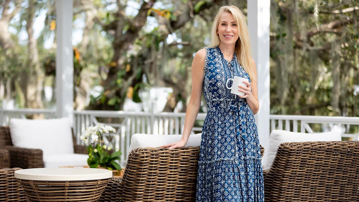 Lee Cotton holds a coffee mug as she stands outside on a patio.