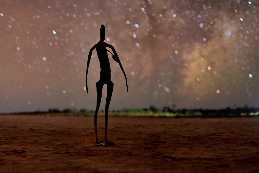 A statue of a person made out metal with stars in the background