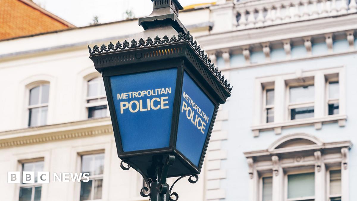 A blue Metropolitan Police lamp post with the words Metropolitan Police in white writing. There's a white building in the background