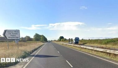 The A15 dual carriageway with a sign pointing to the Elsham Wolds Industrial Estate. The sky is blue with some clouds.
