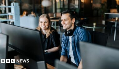 Happy male and female entrepreneurs watching computer screen sitting in tech startup office - stock photo