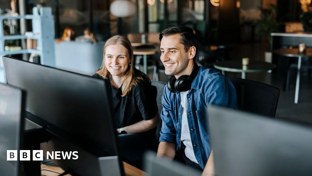 Happy male and female entrepreneurs watching computer screen sitting in tech startup office - stock photo