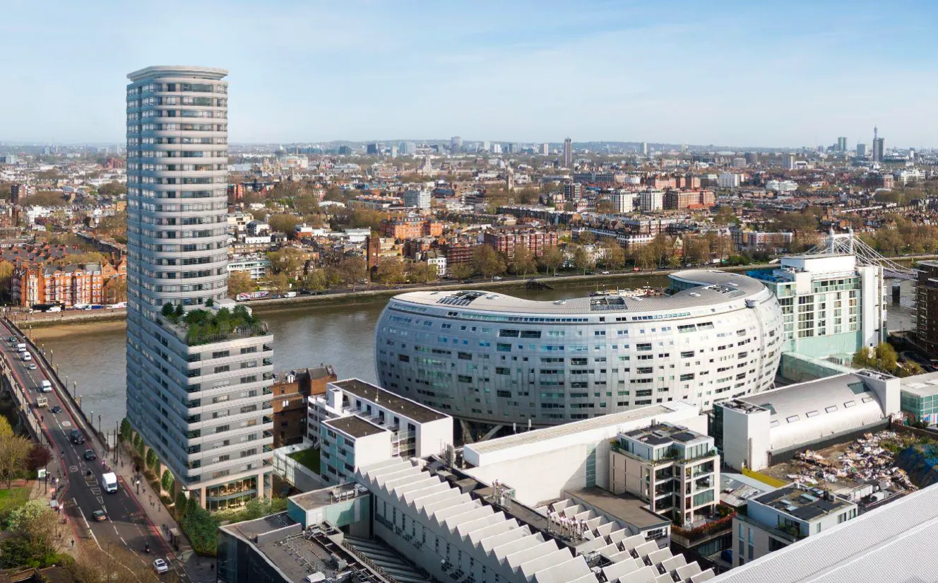 Aerial view of the One Battersea Bridge development, a tall cylindrical building next to a curved building and a bridge over a river.