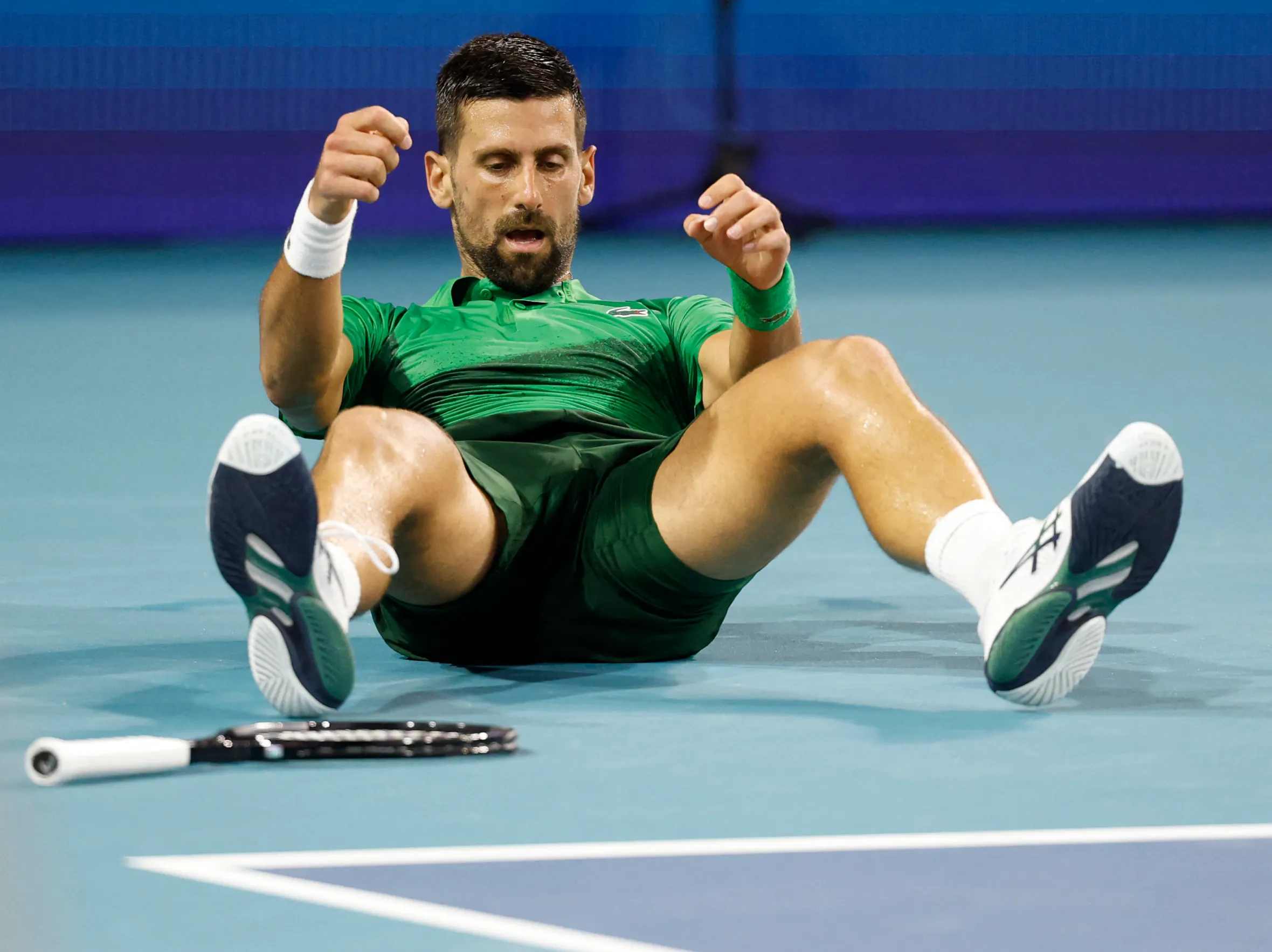 Novak Djokovic sitting on the court after losing a point at the Miami Open.