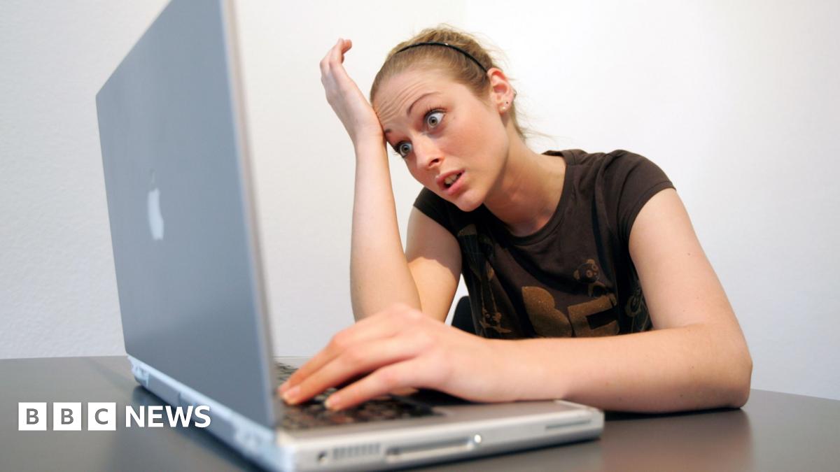 Professor David Hughes is sitting in front of a grey wall and looking directly at the camera. He is wearing a navy suit, tie and white shirt. He has short black hair.