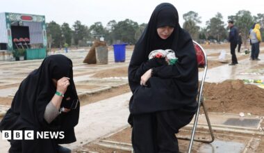 Two women crouch at the grave of a relative in a cemetary in Tehran on 16 March