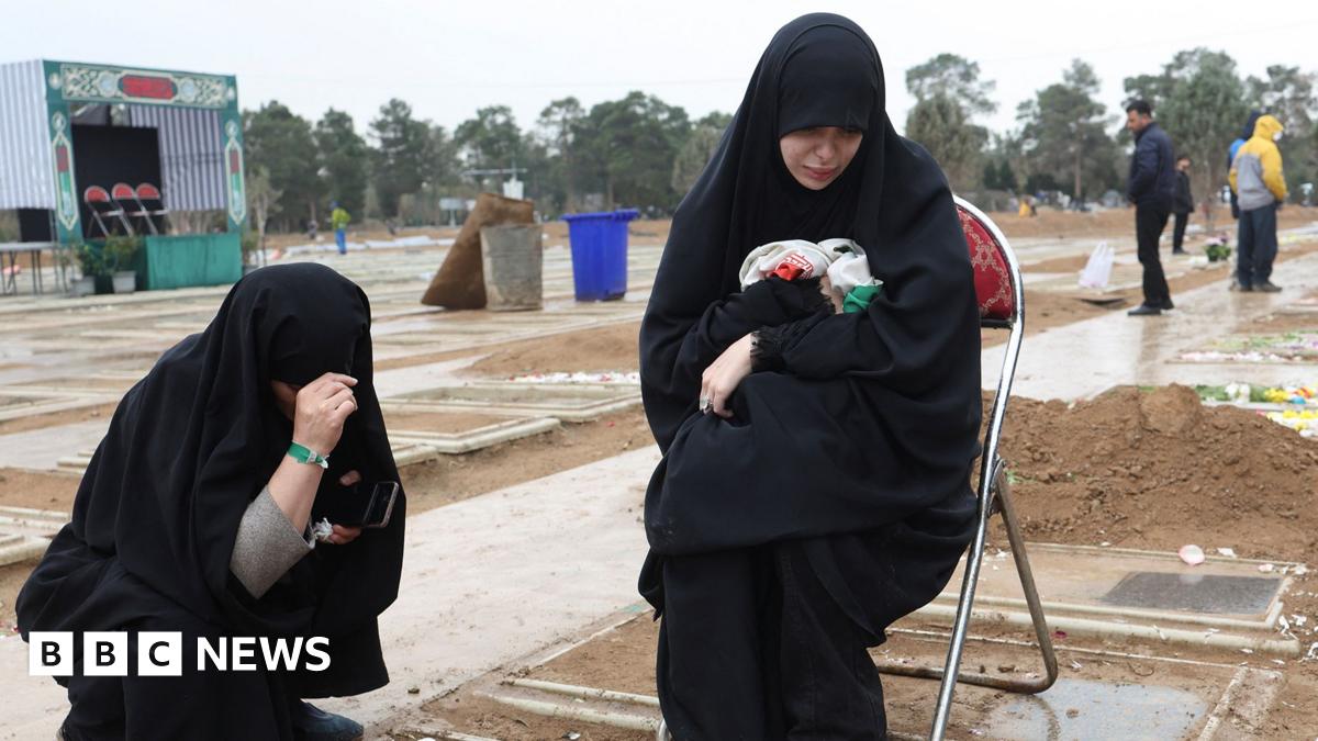 Two women crouch at the grave of a relative in a cemetary in Tehran on 16 March