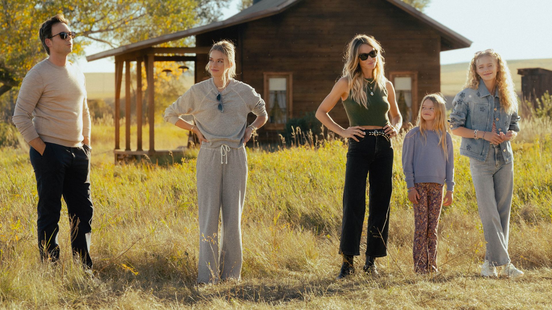 A line of people stand in a field with their hands on their hips