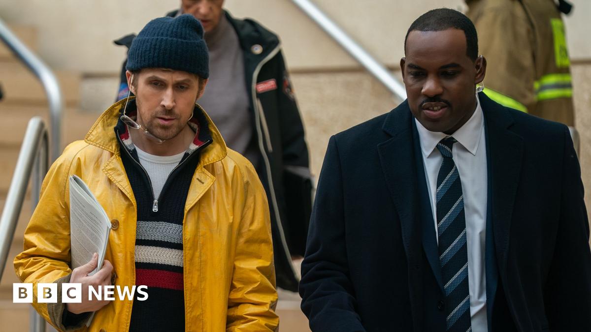 A promotional still from the film shows on the left Gosling as Ryland Grace and on the right Lionel Boyce as security guard Carl as they walk down a set of stairs during the film.
