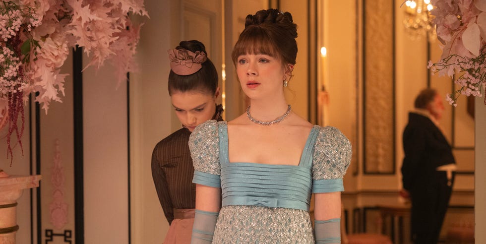 two women in elegant period attire at a formal gathering