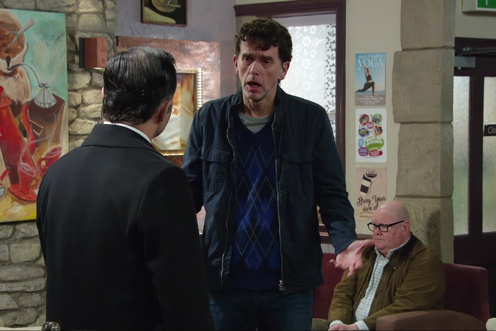 Paddy sitting in the background as Marlon speaks to Graham in Emmerdale