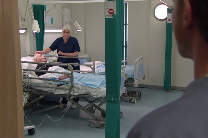 Doctor Todd standing over her father and eyeing Jacob with fury in Emmerdale