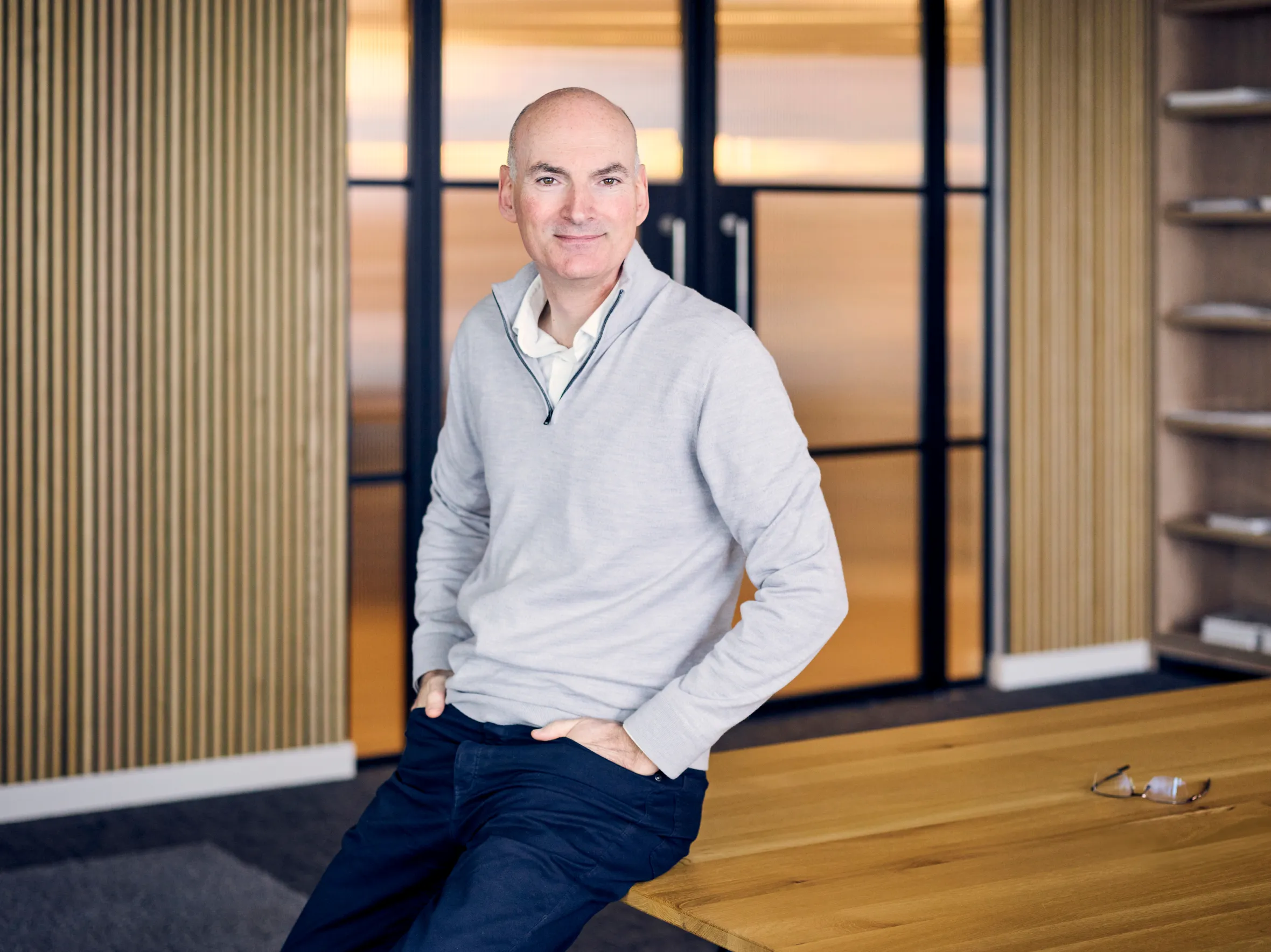 Andrew Williamson, managing partner at Cambridge Innovation Capital, smiles while sitting on a table.
