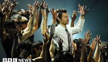 Harry Styles performs during the Brit Awards 2026 at Co-op Live, Manchester wearing a shirt and tie surrounded by back-up dancers.
