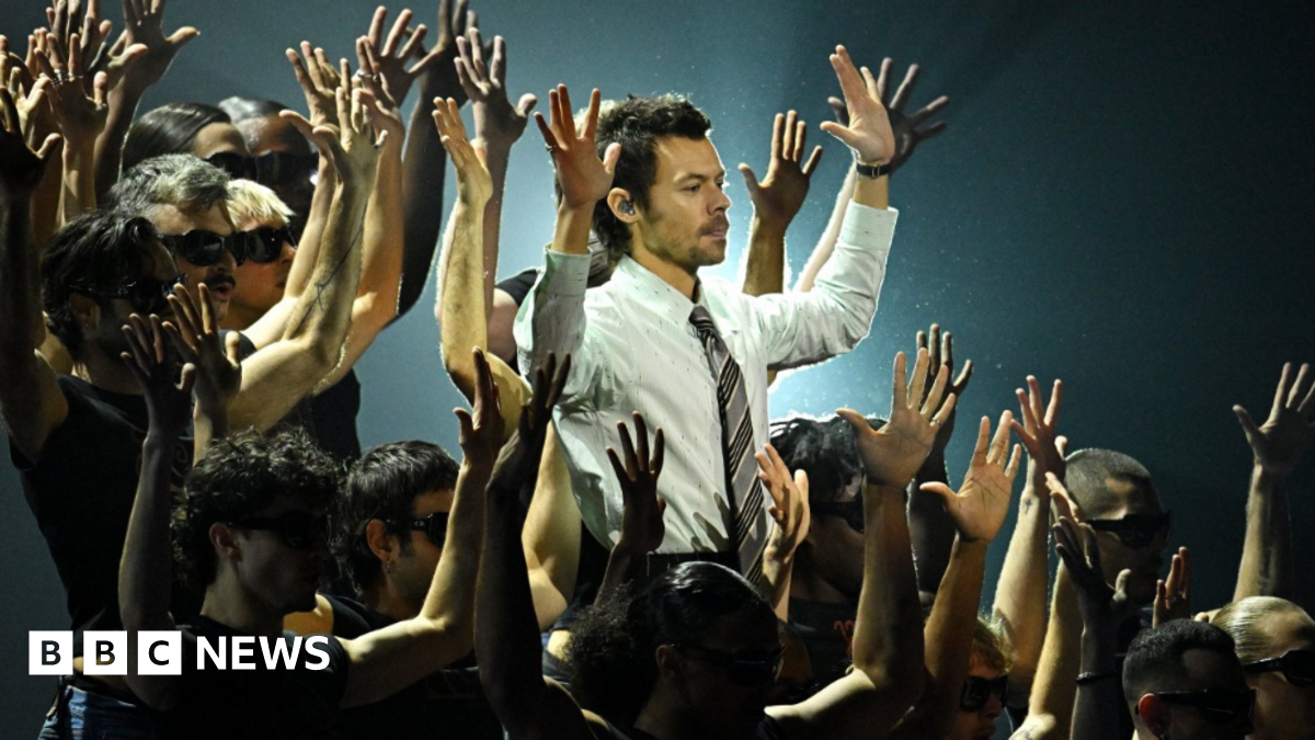 Harry Styles performs during the Brit Awards 2026 at Co-op Live, Manchester wearing a shirt and tie surrounded by back-up dancers.