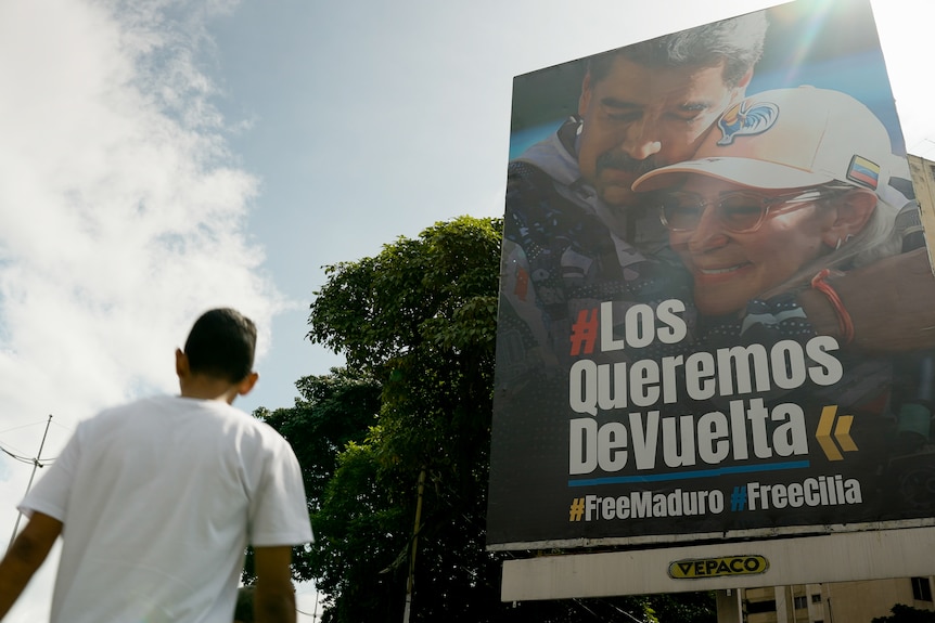 A man looks at a tall billboard with a message written in Spanish on it