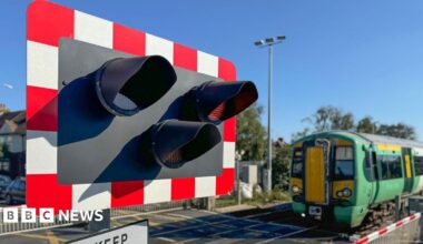 A railway level crossing with a green Southern train going across it.