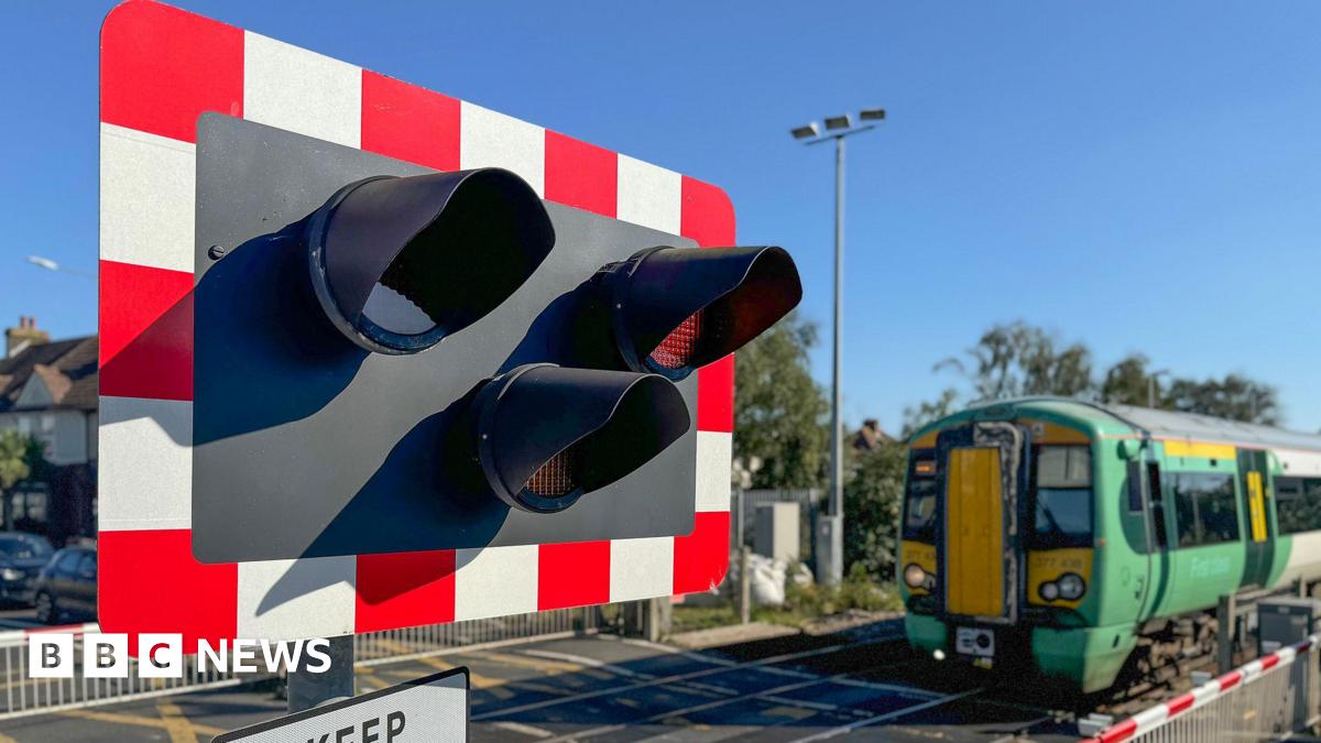 A railway level crossing with a green Southern train going across it.