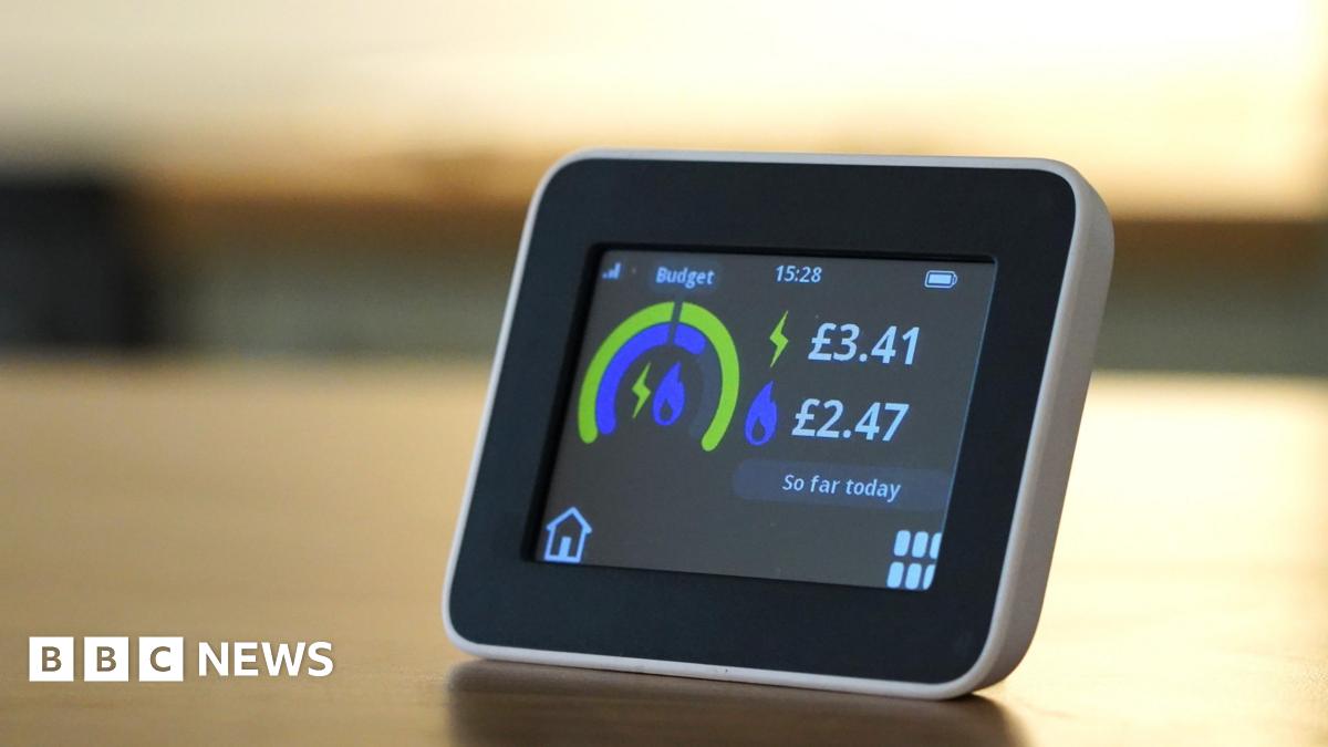 A small smart electricity meter on a table. It has a display that shows a graphic in blue and green contrasting the budget vs the cost of the energy used so far.