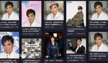 Kris Jenner, wearing a pair of thick black sunglasses and dangling earrings, smiles for photographers at a red carpet event.