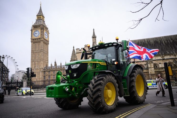 Farmers gathered in protest holding banners and signs, advocating for agricultural rights and policy reforms in rural sett...