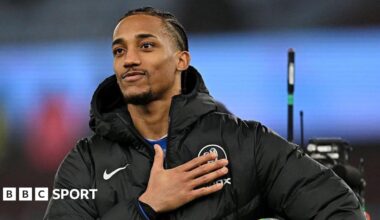 Joao Pedro pats the Chelsea badge while facing towards chanting fans