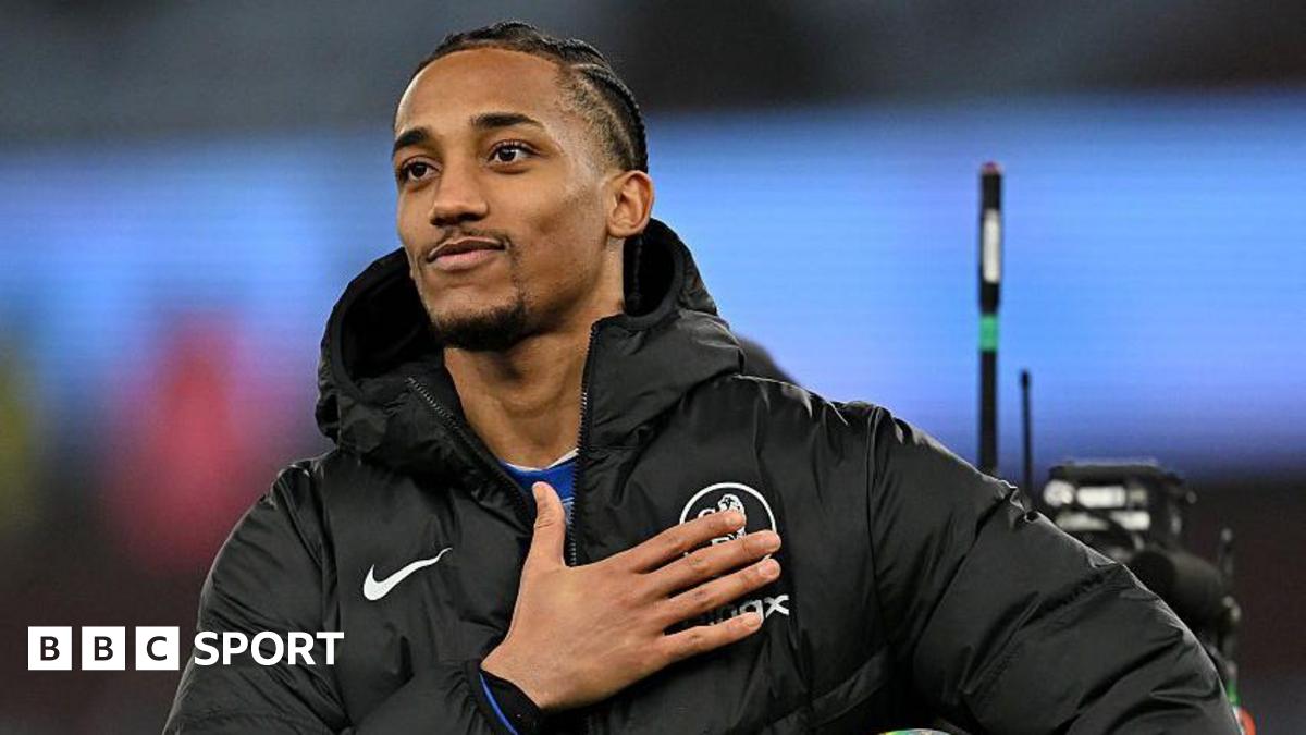 Joao Pedro pats the Chelsea badge while facing towards chanting fans