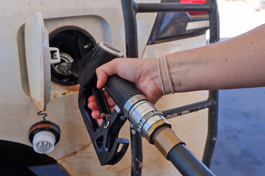 A person fuels up their vehicle at a petrol station close up.