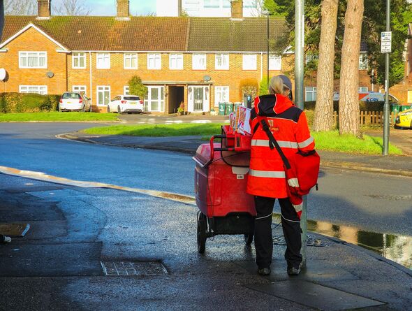 Royal Mail worker pushing mail trolley on street