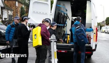Police officers pack up outside a van on an urban street.